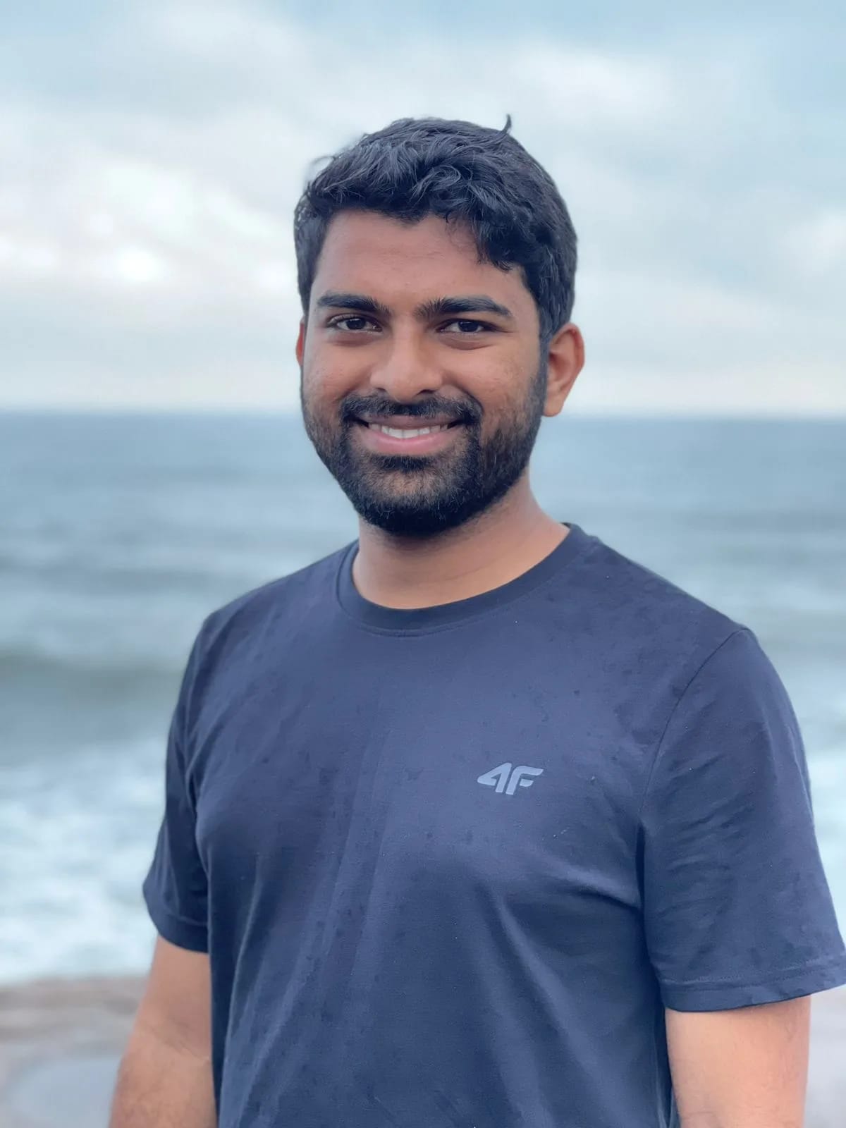 Man wearing a black t-shirt standing at a beach shore