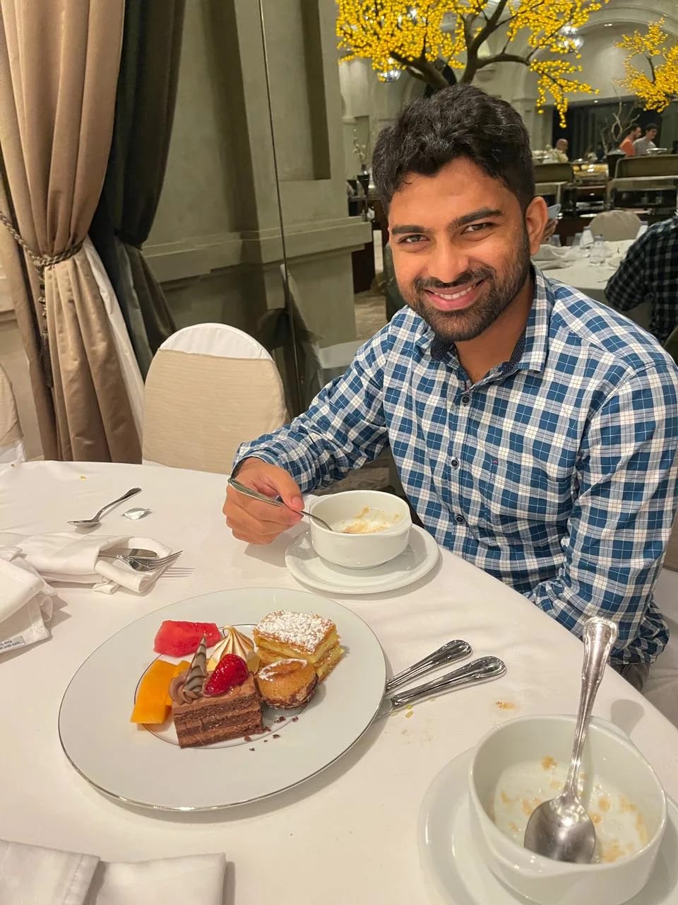 Man wearing a blue checkered shirt at a dining table having cake