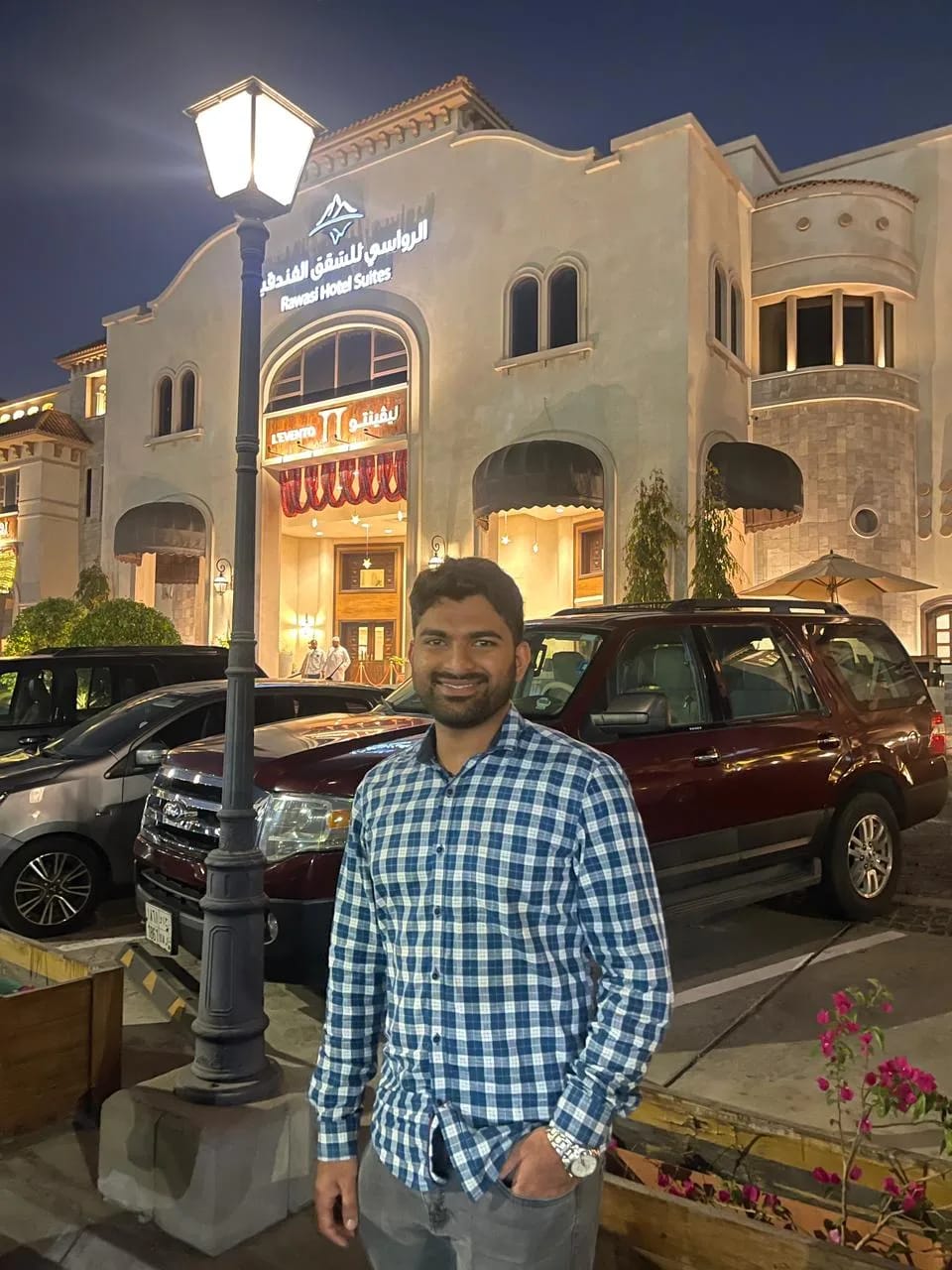 Man wearing a blue checkered shirt standing outside a hotel