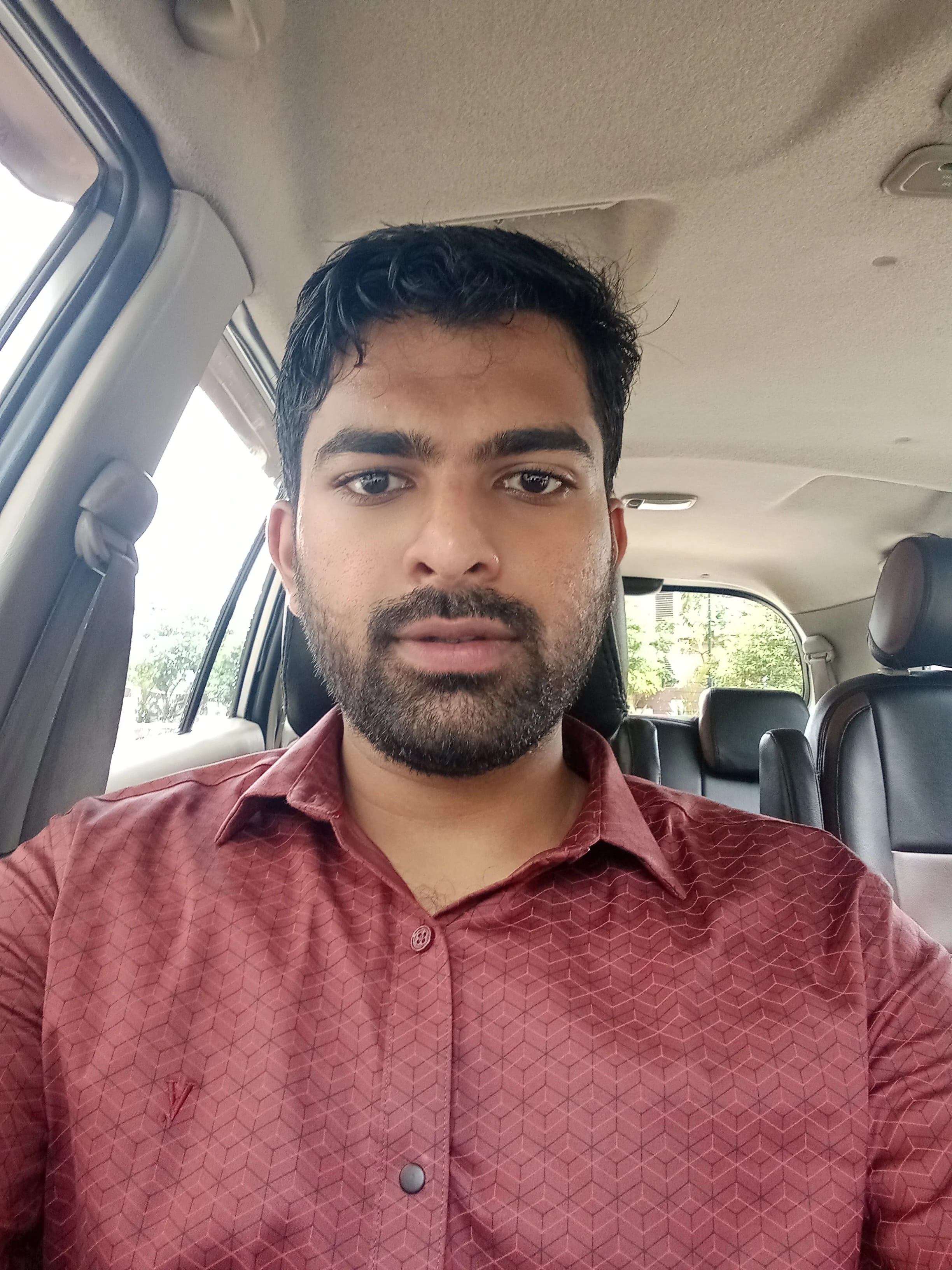 Selfie of a man wearing a red shirt in a car